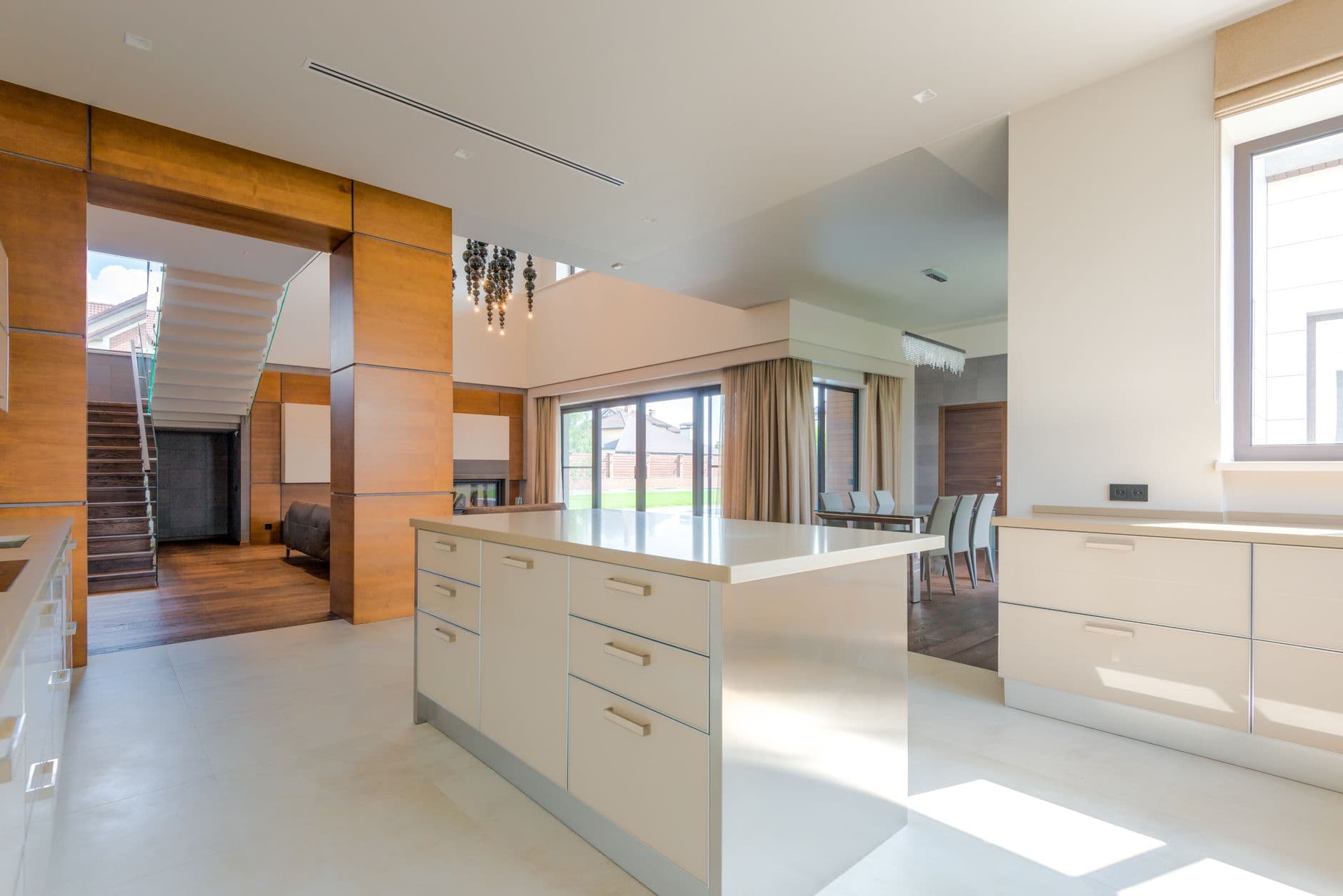 Open kitchen with pale stone floor tiles, warm cabinetry and a long island