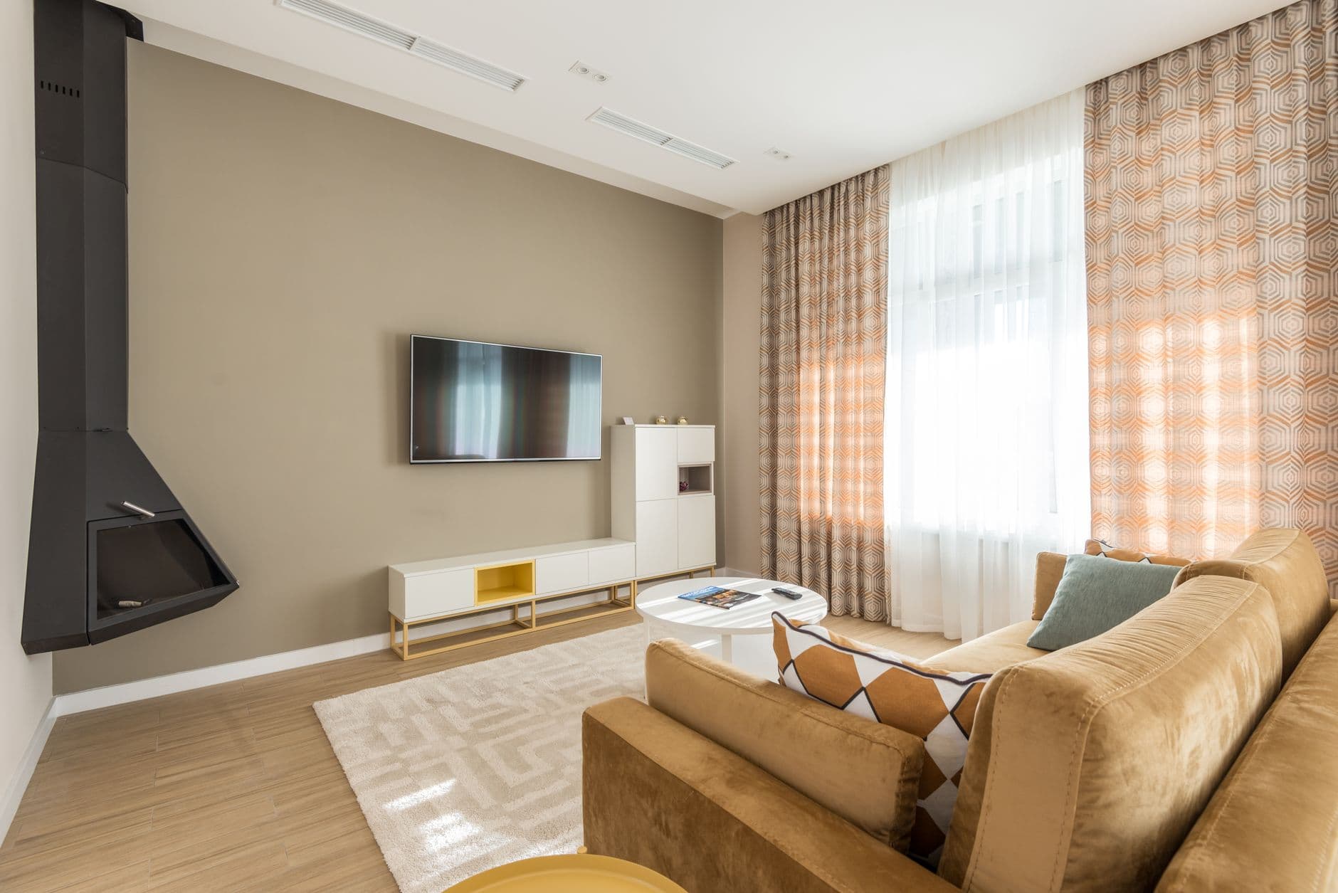 Living room with a softly rounded wall beside a low television cabinet and brown sofa