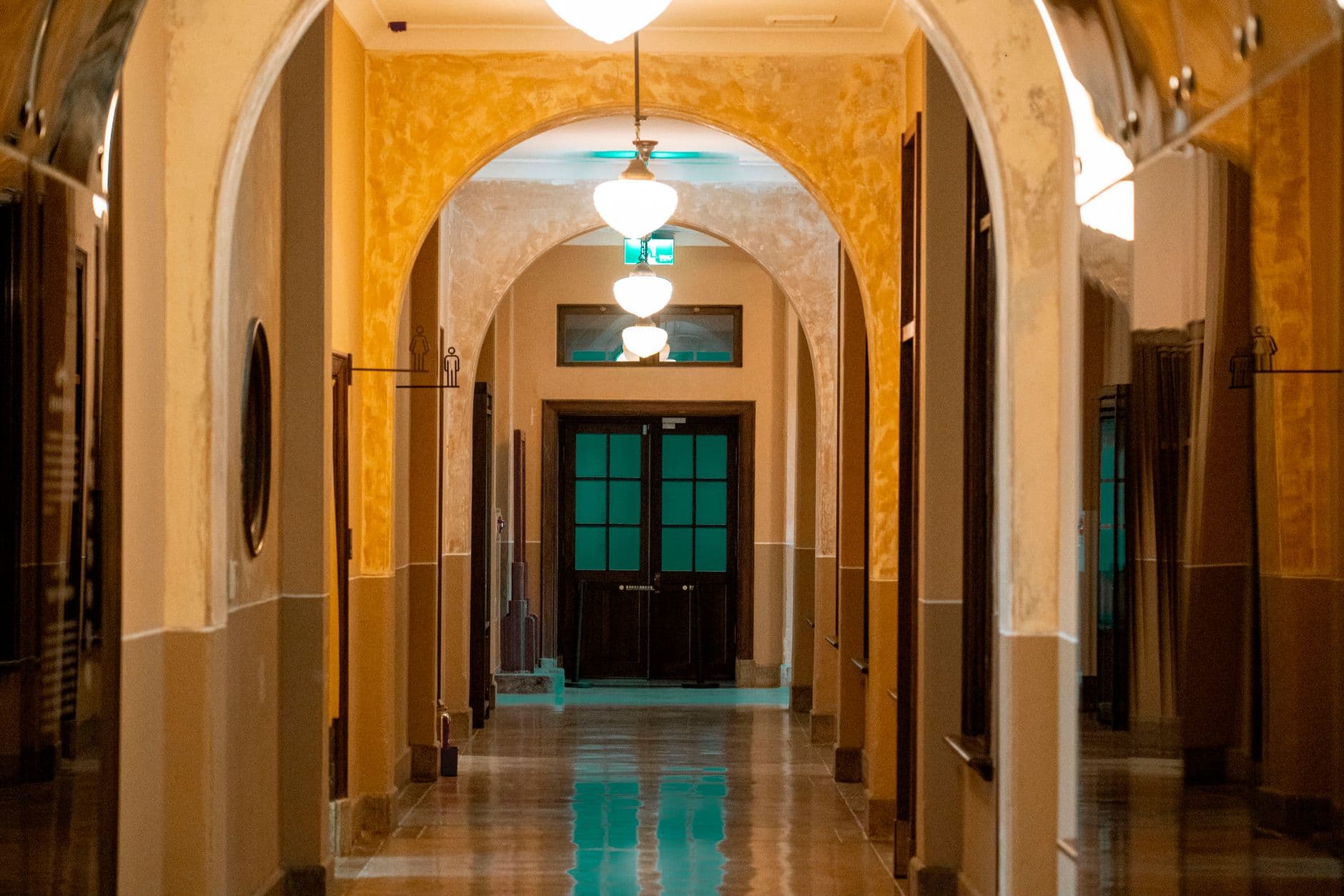 Warm hallway with a tall arched opening and light visible in the room beyond