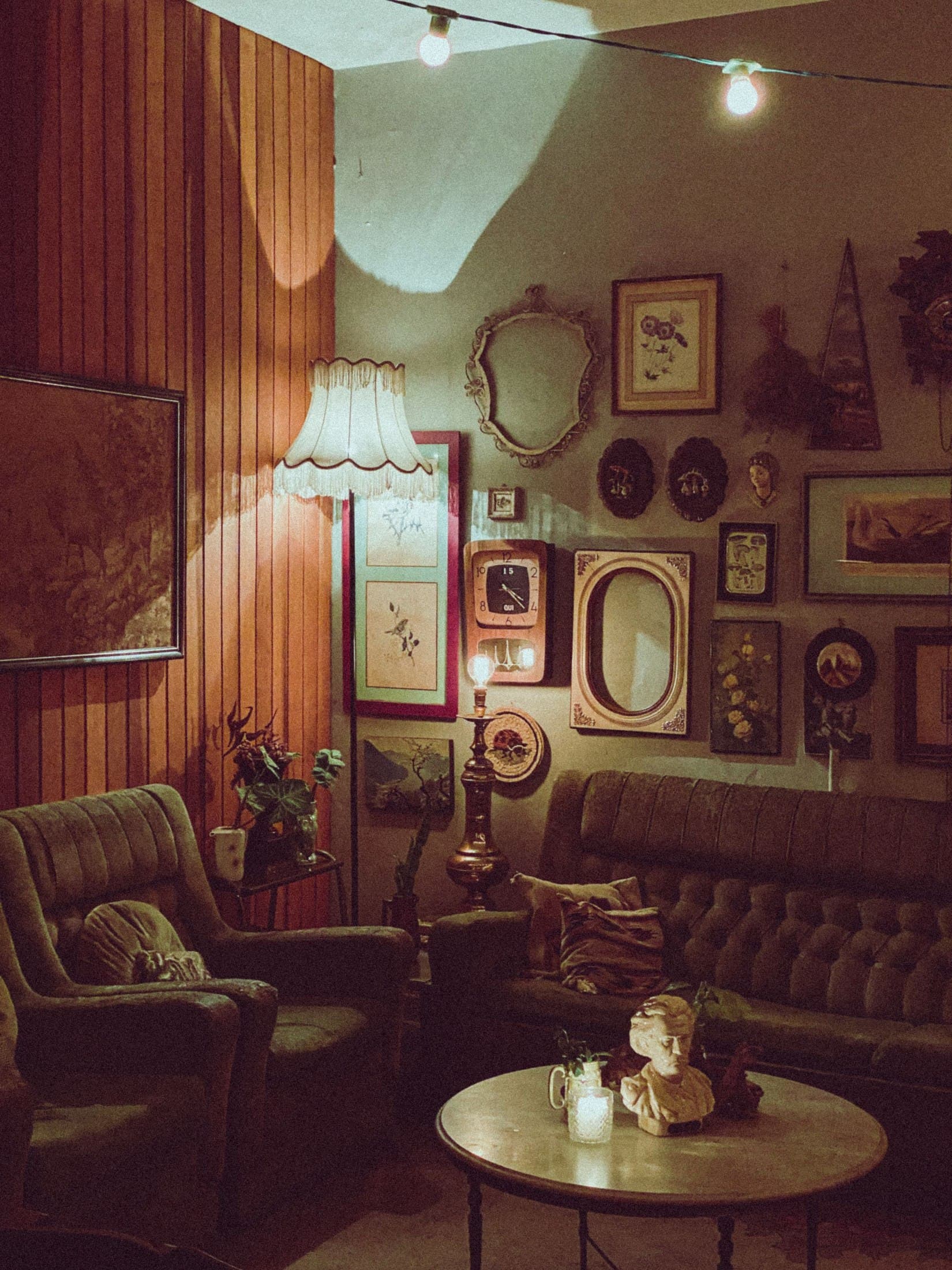 Warm period living room with vintage seating, portraits and timber walls