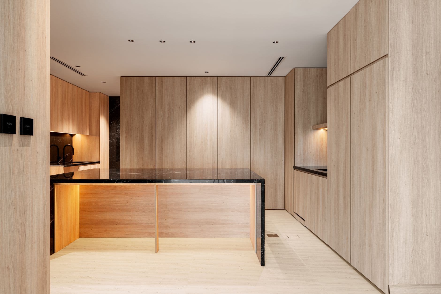 Minimal kitchen with warm timber cabinetry, a pale worktop and a dark stool