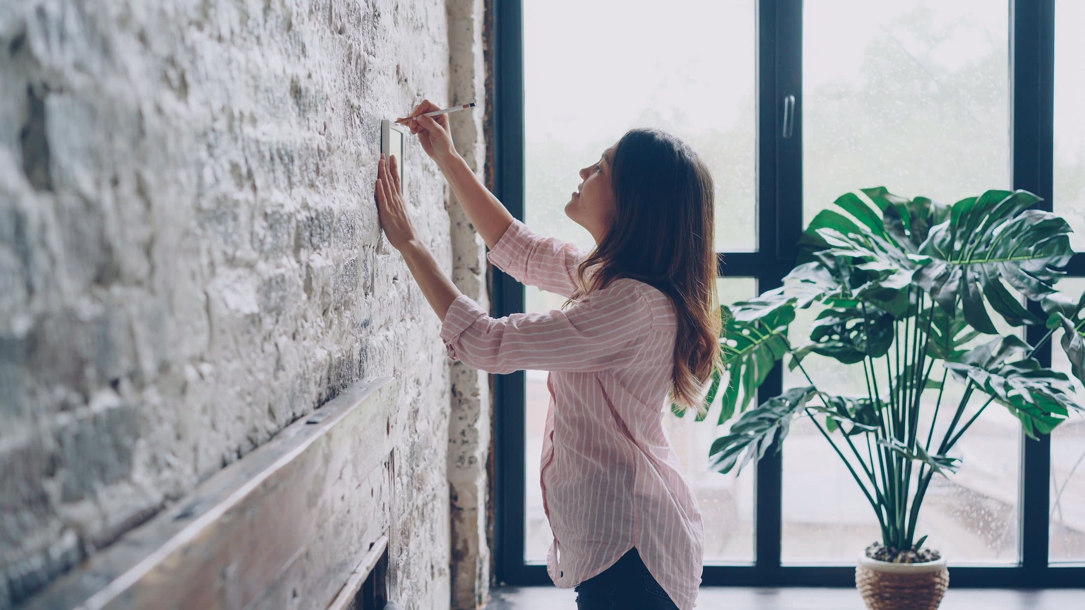 Person measuring a wall in a light-filled interior