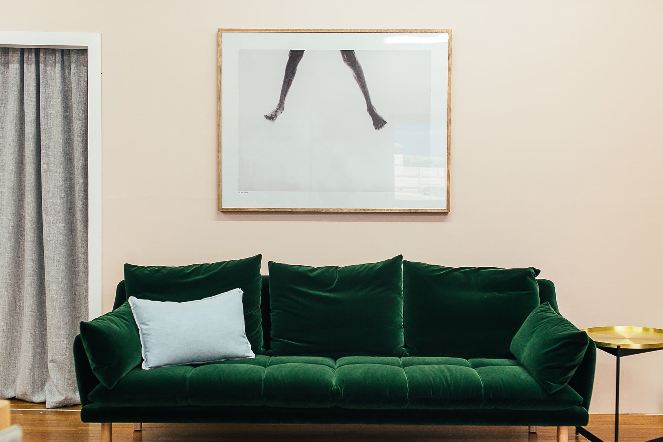 Framed artwork centred above a green sofa