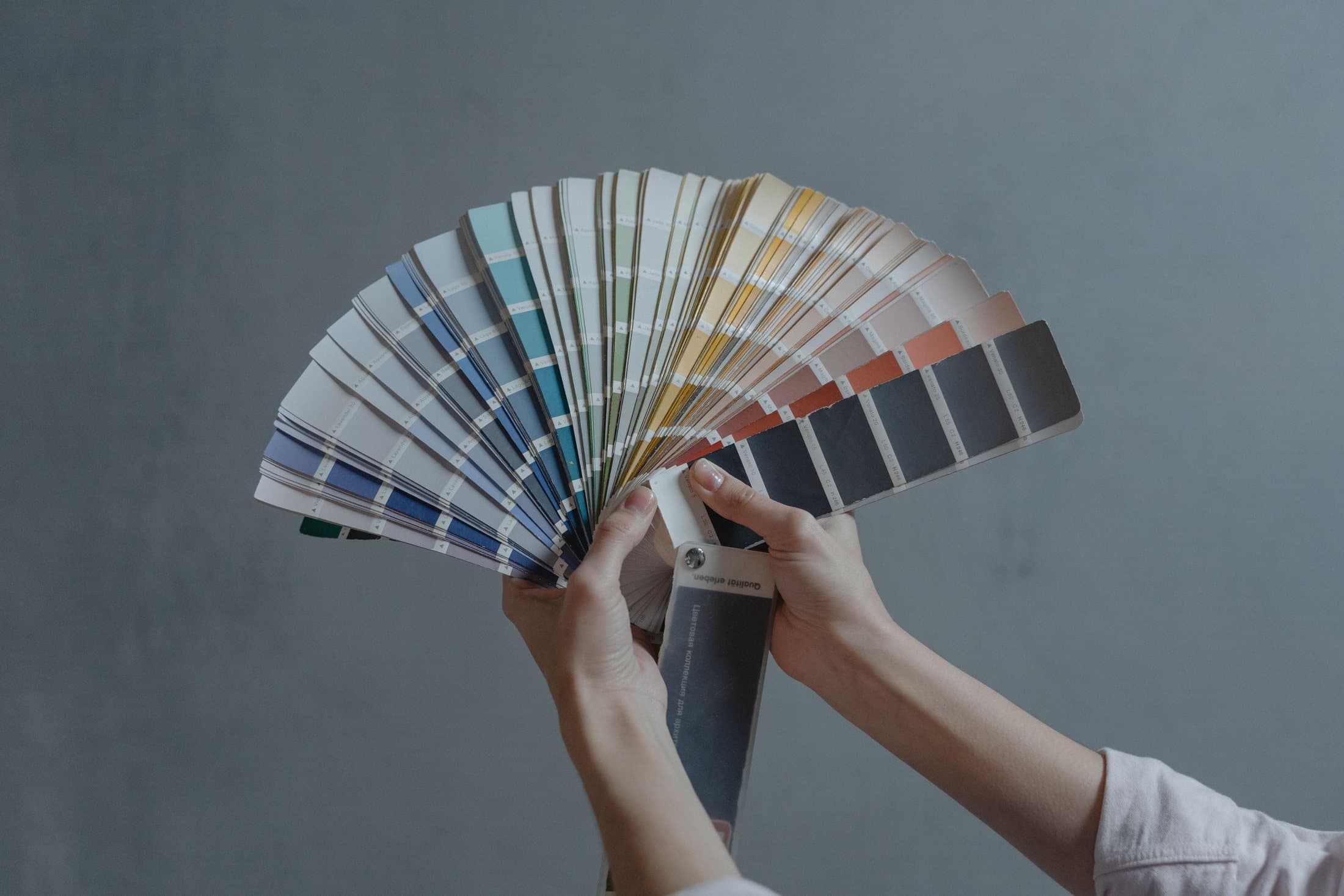 Hands comparing a fan of interior paint colours