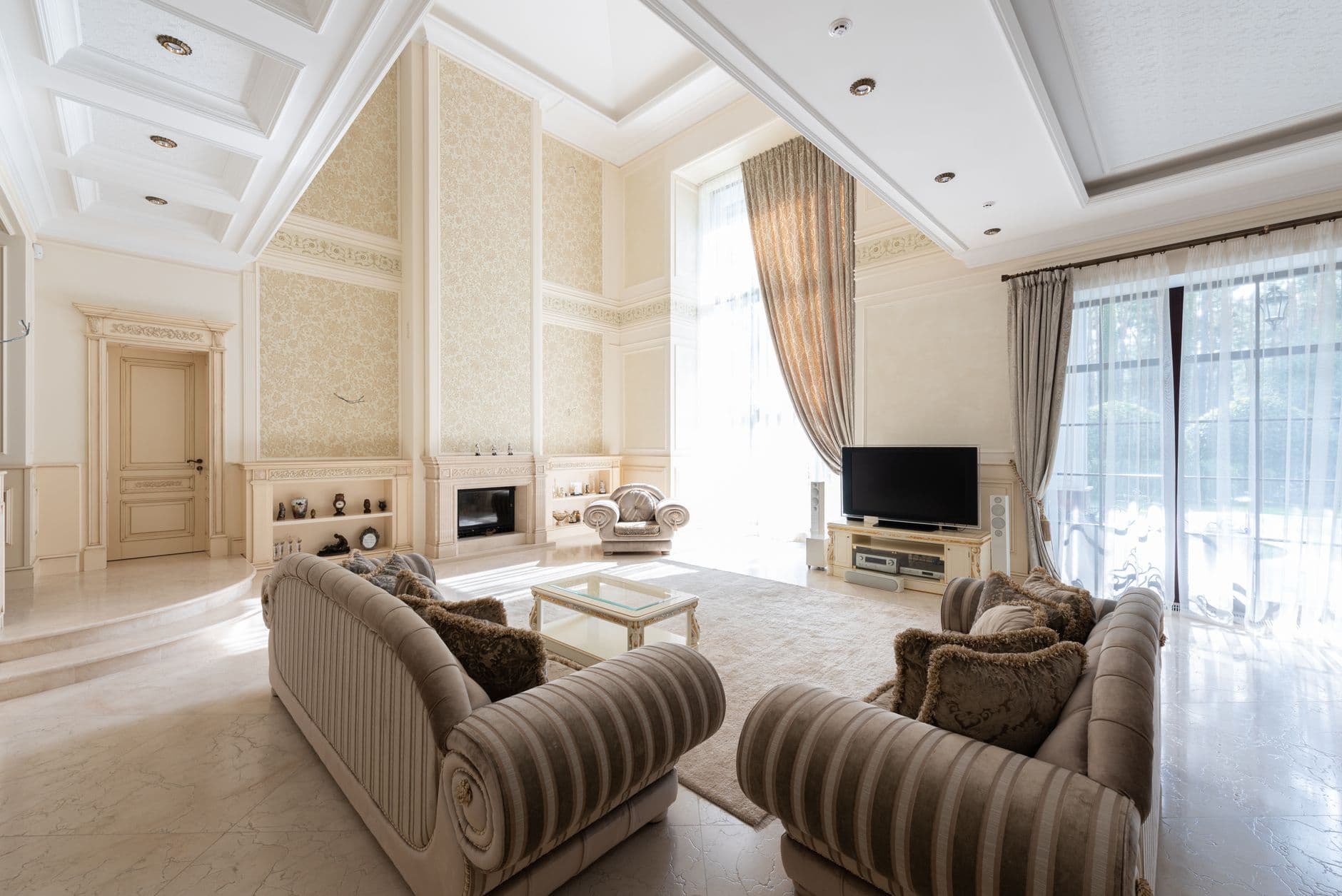 Interior of spacious living room with sofas near table on carpet next to TV and windows with curtains
