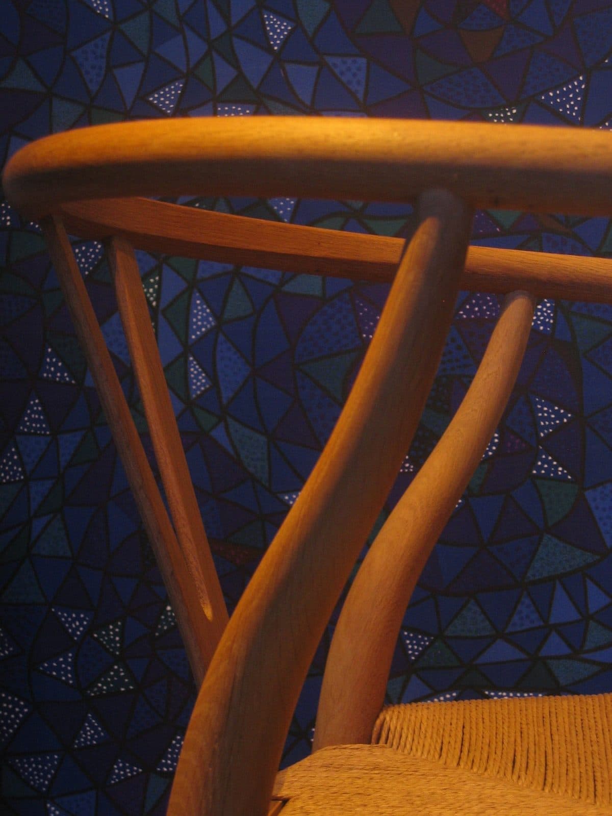 The woven seat and curved wooden back of a Wishbone Chair.